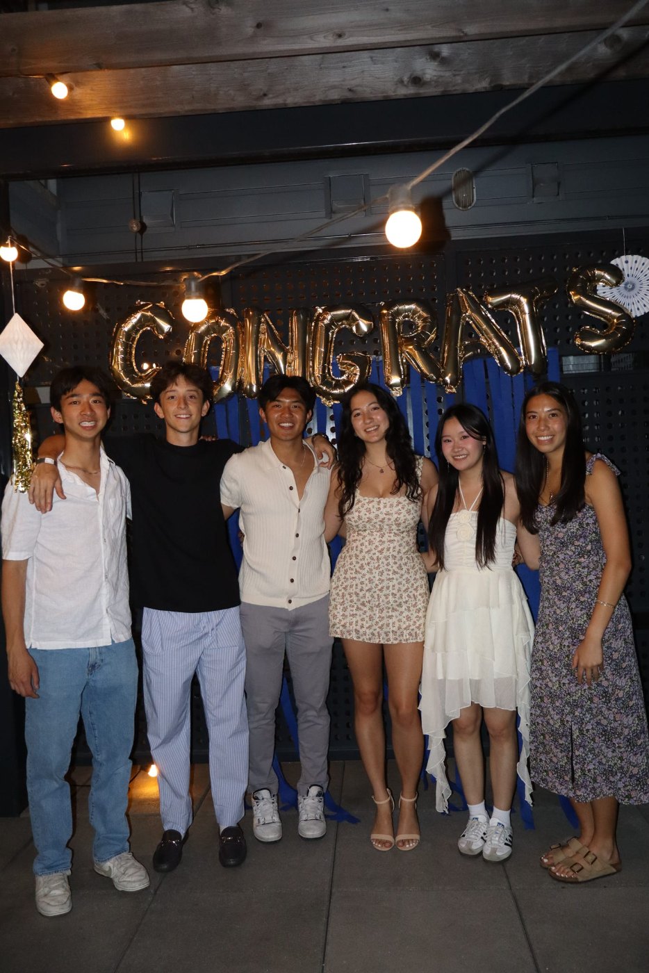 Psi Eta Mu members together at a celebration under a Congrats balloon banner